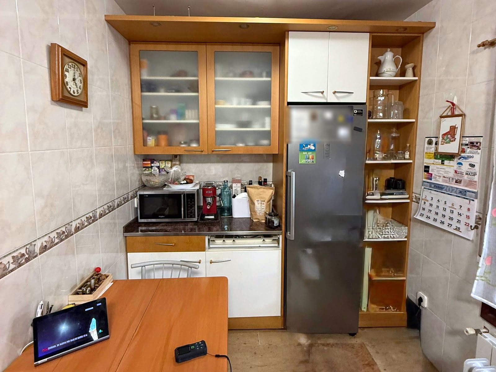 El otro lado de la cocina antes de la reforma, con los muebles de madera, la nevera suelta y la mesa plegable